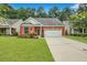 Charming brick home showcasing a well-manicured lawn, lush landscaping, and a two-car garage at 215 Angora Way, Summerville, SC 29485