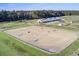Equestrian center featuring a large riding arena, modern barn, and expansive green pastures with forest views at 4086 Lady Banks Ln, Ravenel, SC 29470