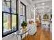 Bright hallway featuring white wainscoting, hardwood floors, and stylish decor with large windows and natural light at 4086 Lady Banks Ln, Ravenel, SC 29470