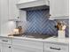 Close up of the kitchen cooktop with a blue backsplash and white cabinets at 4086 Lady Banks Ln, Ravenel, SC 29470