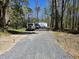 Long gravel driveway leading up to a garage and home with a few parked cars at 4532 S Carolina # 41, Huger, SC 29450