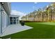 Expansive backyard showcasing lush green grass, a screened-in porch, and a backdrop of mature trees at 460 Cool Bend Ln, Summerville, SC 29486