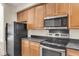 Updated kitchen showcasing stainless steel appliances, wooden cabinets, and sleek black countertops; blending style and functionality at 4913 Lake Palmetto Ln, North Charleston, SC 29418