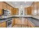 Well-lit kitchen featuring wood cabinets, stainless steel appliances, and dark countertops for a modern feel at 4913 Lake Palmetto Ln, North Charleston, SC 29418