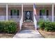Close-up of a brick porch with a white railing, stairs leading to an arched front door with an American flag at 5367 Boone Run, Hollywood, SC 29449