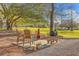 Backyard patio with a wood burning fireplace, seating and grilling area surrounded by mature trees and grass at 5758 Chisolm Rd, Johns Island, SC 29455