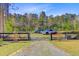 Gravel driveway leading to a fenced area with several parked vehicles, surrounded by mature trees at 614 Cummings Chapel Rd, Ridgeville, SC 29472