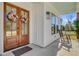 Charming covered porch with rocking chair and beautiful wooden front door with floral wreaths at 614 Cummings Chapel Rd, Ridgeville, SC 29472