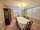 Formal dining room with wooden table, chairs, hutch and chandelier, bathed in natural light from shuttered windows at 8524 Cane Branch Rd, Ruffin, SC 29475