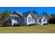 Charming white home featuring a gray roof and vibrant blue shutters, surrounded by lush landscaping at 8524 Cane Branch Rd, Ruffin, SC 29475