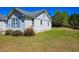 Spacious side yard featuring a white home, flowering bushes, and a backdrop of lush trees at 8524 Cane Branch Rd, Ruffin, SC 29475