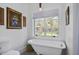 Bright bathroom with a clawfoot tub under a window, and a modern toilet at 10044 Randall Rd, McClellanville, SC 29458