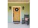 A welcoming front door featuring a wreath, decorative sconces, and a rocking chair on the porch at 10044 Randall Rd, McClellanville, SC 29458