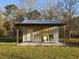 Backyard outbuilding features a metal roof, a sitting area on a concrete pad, and a wooded backdrop at 10044 Randall Rd, McClellanville, SC 29458