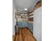 Pantry with custom blue cabinets, open shelving, butcher block countertops, and hardwood floors at 10044 Randall Rd, McClellanville, SC 29458