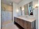 Bright bathroom features a double vanity with stone countertop and walk-in shower with glass door and tile surround at 108 Salthouse Ln, Kiawah Island, SC 29455