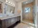 Bright bathroom features a double vanity with stone countertop and walk-in shower with pebble tile flooring at 108 Salthouse Ln, Kiawah Island, SC 29455