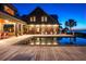 Gorgeous rear view of the home at night featuring a pool, deck with chairs, and beautifully lit landscaping at 108 Salthouse Ln, Kiawah Island, SC 29455