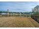 View of the backyard with a fence, lake, and houses in the distance at 1081 Magnolia Warbler Way, Ravenel, SC 29470