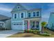 Charming two-story home with pale blue siding, white trim, bright red door, and well-manicured landscaping at 1081 Magnolia Warbler Way, Ravenel, SC 29470