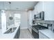 A well-lit kitchen with stainless steel appliances, sleek white countertops and cabinets, and an island sink at 1081 Magnolia Warbler Way, Ravenel, SC 29470
