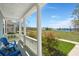 Covered front porch featuring blue Adirondack chairs, porch railing and view of common green space at 122 Yorkshire Dr, Moncks Corner, SC 29461
