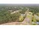 A high aerial showcases the property's home, barns, and tree filled acreage with bordering open land and neighboring houses at 1298 French Santee Rd, Jamestown, SC 29453