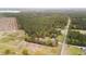 High angle aerial of the property featuring a home, barns, and manicured yard surrounded by trees and grassy open land at 1298 French Santee Rd, Jamestown, SC 29453