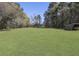 Vast backyard showcasing a well-manicured lawn, mature trees, and storage shed with a partially covered structure at 1298 French Santee Rd, Jamestown, SC 29453