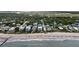 Aerial view showcasing beachfront homes, sandy beach, and ocean waves with lush greenery and neighborhood streets at 1702 Palmetto Blvd, Edisto Island, SC 29438