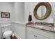 Powder room featuring a round mirror, granite vanity, and elegant wall accents at 1702 Palmetto Blvd, Edisto Island, SC 29438