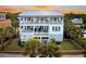 Beautiful multi-story home with a metal roof, white trim, and multiple decks overlooking manicured lawn with palm trees at 1702 Palmetto Blvd, Edisto Island, SC 29438