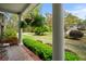 Covered porch with lush hanging plants, views of the yard, and classic brick detailing at 202 Woodland Dr, Summerville, SC 29485