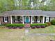Charming brick home featuring a blue door, covered porch with columns, and manicured landscaping at 202 Woodland Dr, Summerville, SC 29485