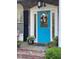 Close-up of a vibrant blue front door with decorative wreath and potted plants on a brick porch at 202 Woodland Dr, Summerville, SC 29485