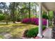 Inviting covered porch with classic columns, lush greenery, and a glimpse of vibrant azaleas in the yard at 202 Woodland Dr, Summerville, SC 29485