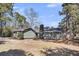 Charming single-story home showcasing a dark gray roof, chimney, and mature trees in the yard at 212 Lake Moultrie Dr, Bonneau, SC 29431