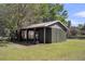 Green outbuilding with an open-air section for parking or storage on a grassy lot under a sunny blue sky at 212 Lake Moultrie Dr, Bonneau, SC 29431
