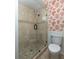 Bathroom with a tiled walk-in shower, coral wallpaper, and white toilet at 24 Waterway Island Dr, Isle of Palms, SC 29451