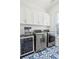 Bright laundry room with white cabinets, stainless steel washer and dryer, and gorgeous blue patterned tile floor at 307 Shoals Dr, Mount Pleasant, SC 29464