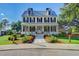 Elegant two-story home with a welcoming front porch, beautiful flower beds, and manicured landscaping at 311 Weston Hall Dr, Summerville, SC 29483