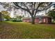A sprawling backyard framed by mature trees and lush greenery, with a glimpse of the home's brick facade at 5040 Lancaster St, North Charleston, SC 29405