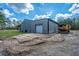 Exterior view of a metal barn with a large roll-up door and heavy equipment adjacent to an open field at 508 Horse Trail Rd, Saint George, SC 29477