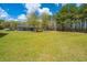 Expansive front yard with mature trees and a large metal outbuilding on a sunny day at 508 Horse Trail Rd, Saint George, SC 29477
