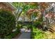 Lush backyard with a stone paver walkway and a small outdoor seating area amongst mature trees and greenery at 56 Parkwood Ave, Charleston, SC 29403