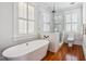 Bathroom with soaking tub, glass-enclosed shower, hardwood floors, and white plantation shutters at 56 Parkwood Ave, Charleston, SC 29403