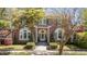 Charming brick home featuring a prominent arched entryway, beautiful landscaping, and mature trees at 56 Parkwood Ave, Charleston, SC 29403