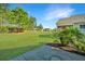 Large manicured backyard featuring mature trees and shrubs with a glimpse of a screened-in porch at 566 Four Seasons Blvd, Summerville, SC 29486