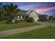 View of charming single story home with manicured lawn and tropical landscaping at sunset at 566 Four Seasons Blvd, Summerville, SC 29486