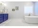 Bright bathroom featuring a soaking tub, blue vanity, and elegant tile flooring at 772 Preservation Pl, Mount Pleasant, SC 29464